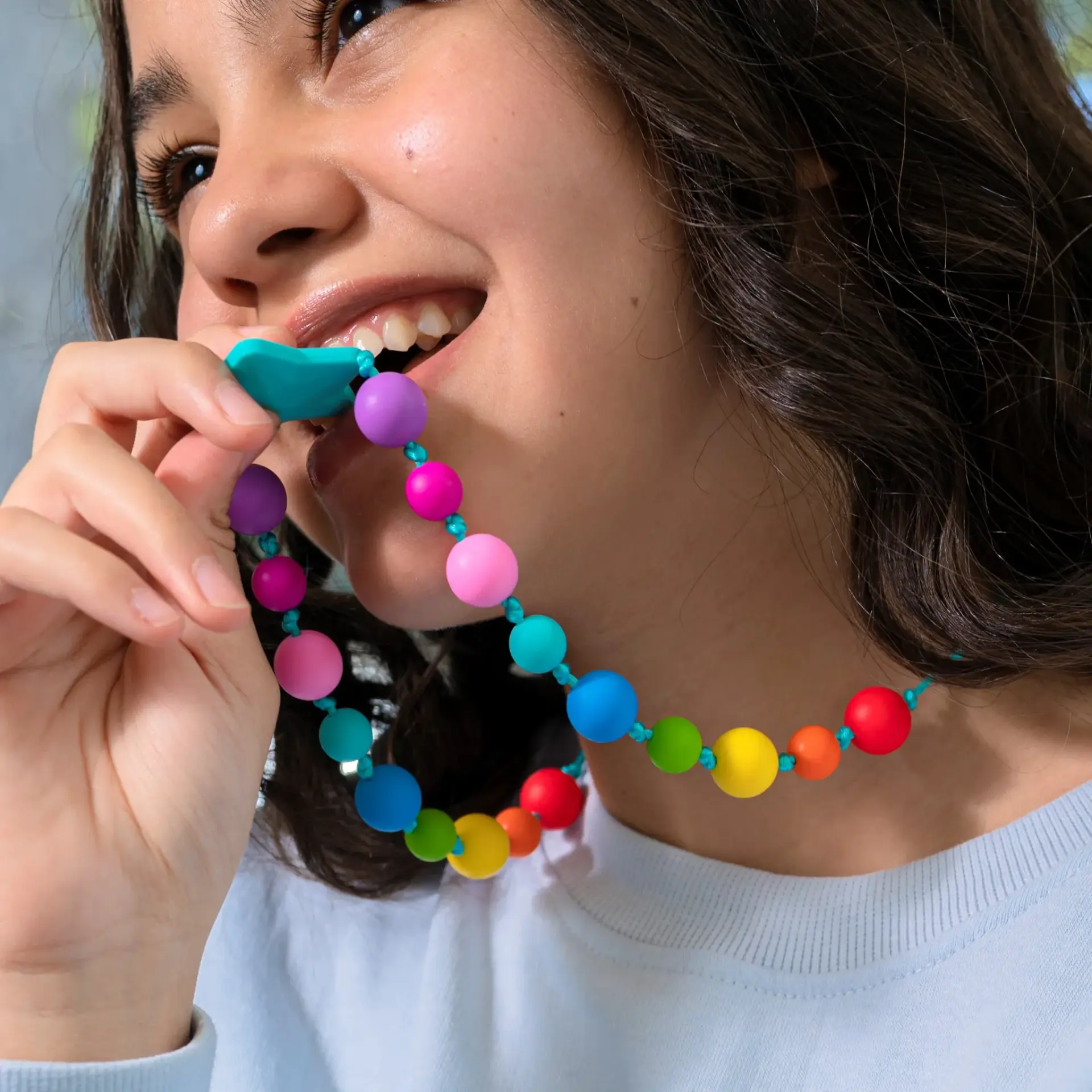 Young person using a colourful sensory chew necklace